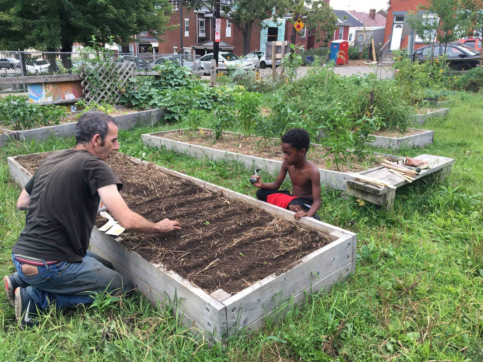 A man and a child work together at a raised garden bed