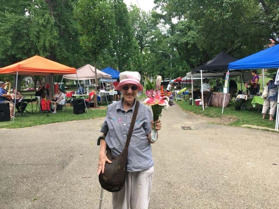 A wonderful person proudly holds up their bouquet of flowers at the outdoor market